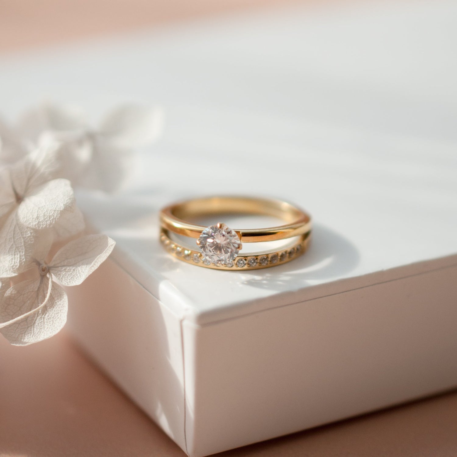 Gold ring with a diamond on a white box with a flower