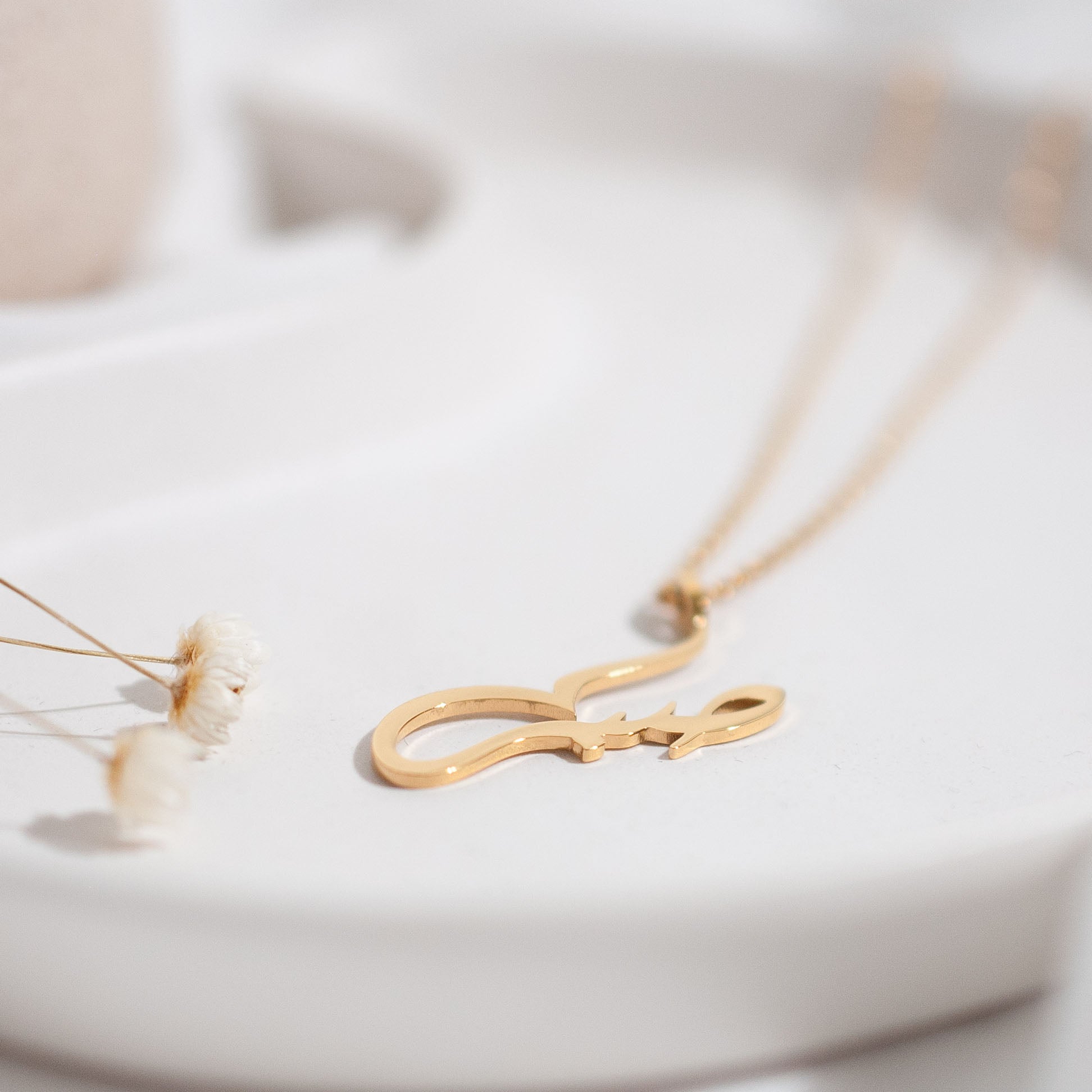 Nimah "Patience" Arabic Necklace displayed on white back ground with small white flowers