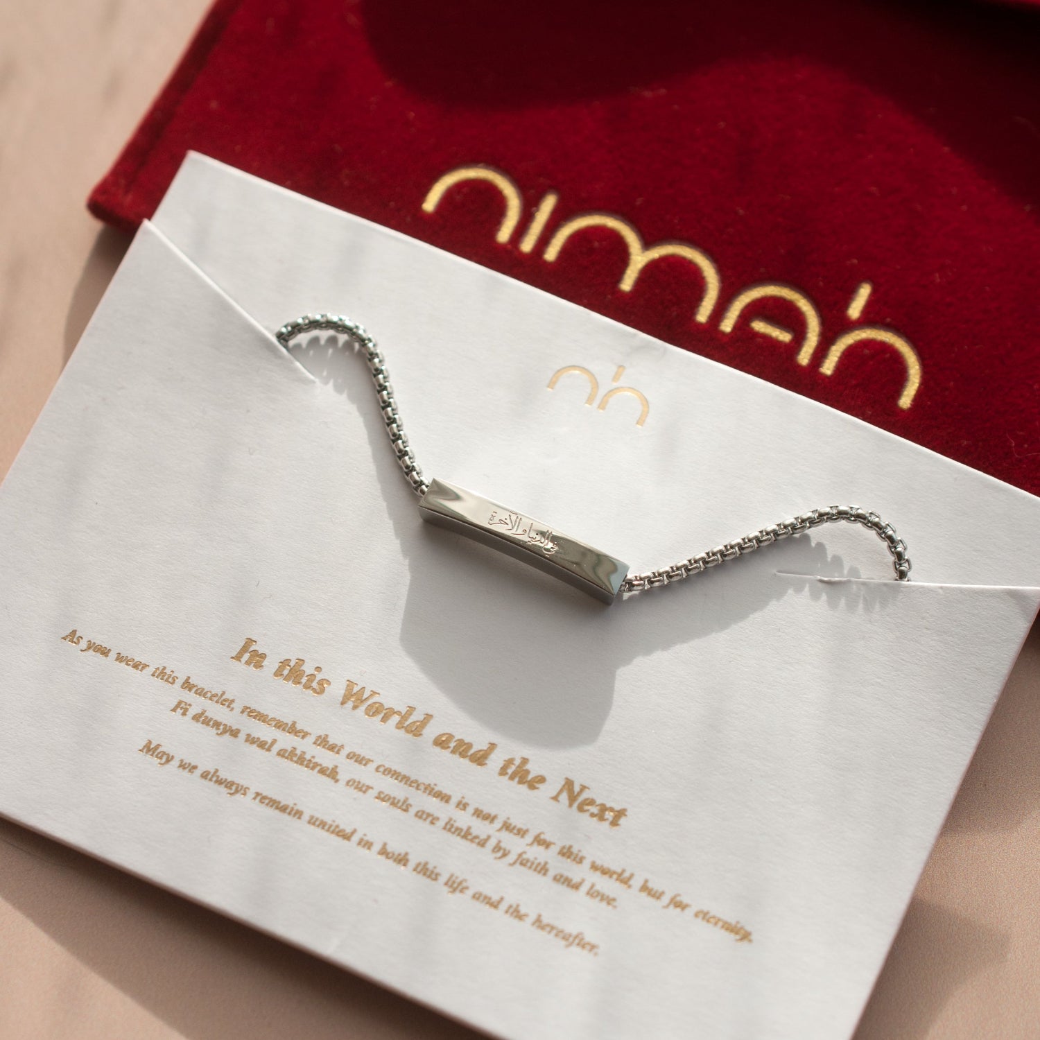 Silver bracelet on a white card with gold text, placed on a red nimah pouch velvet