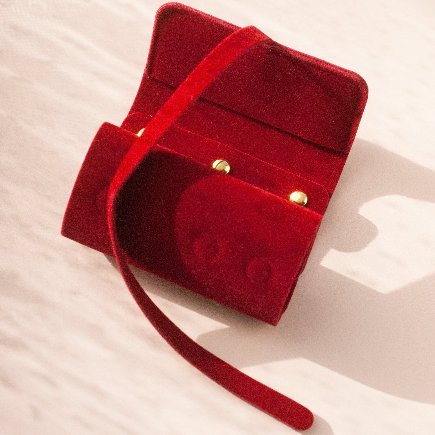 Red velvet jewelry box with a strap on a light background