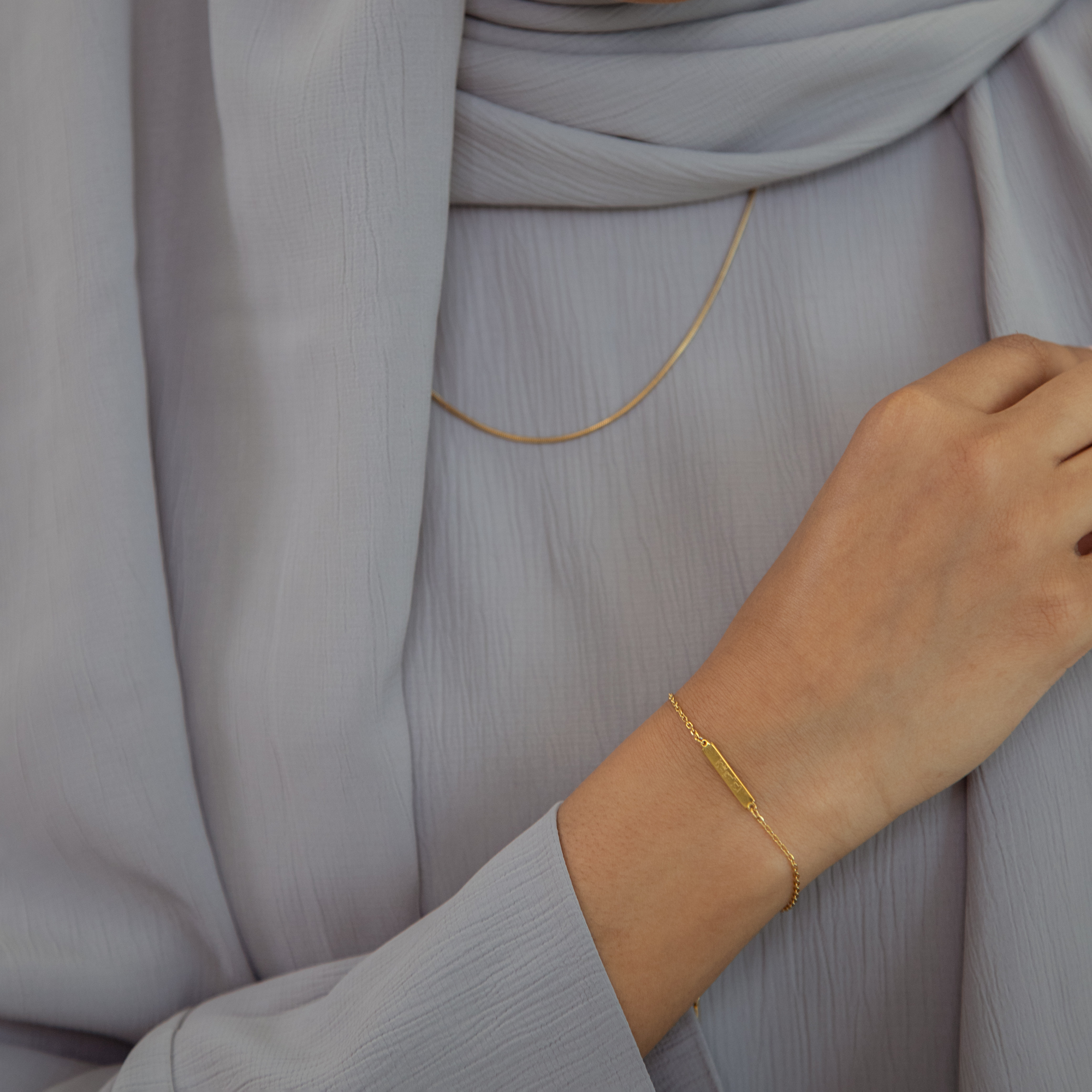 model styling the 'with hardship comes ease' Arabic gold bracelet and gold chain
