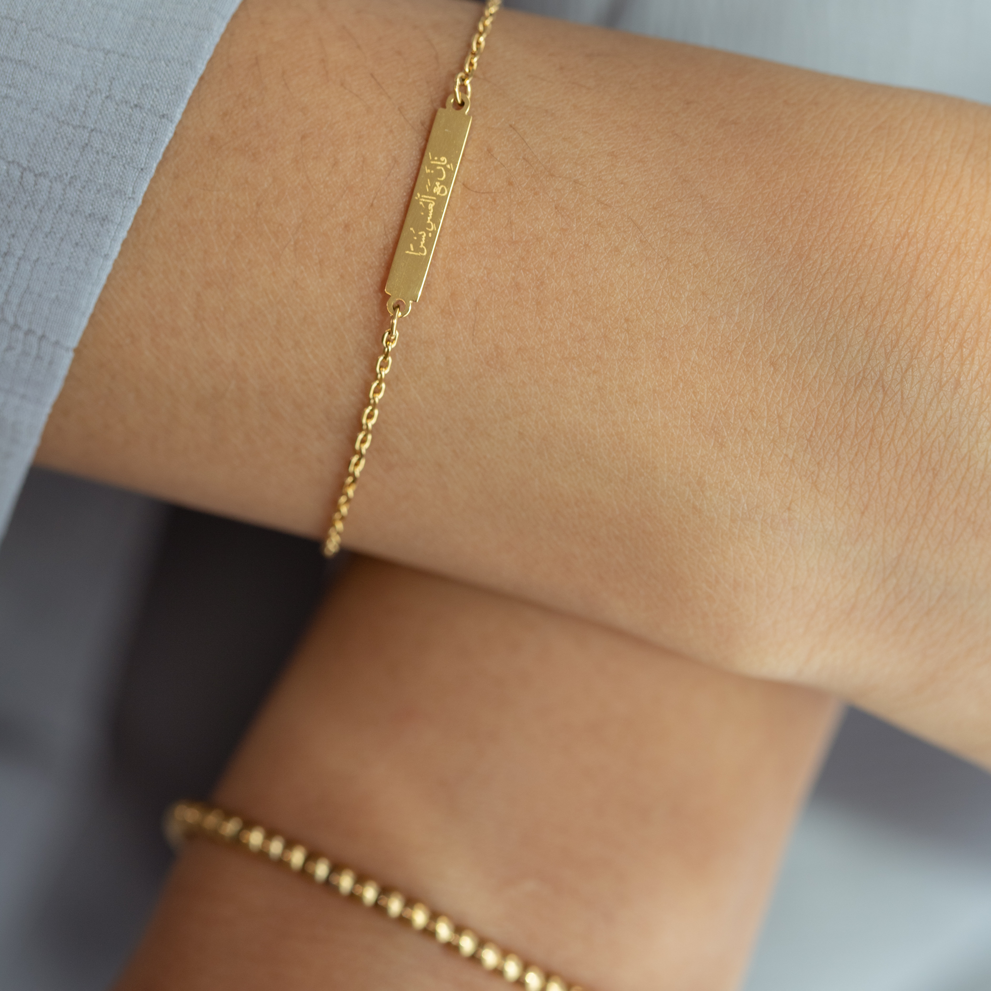 model wearing the islamic bracelet in gold 'with hardship comes ease' engraved