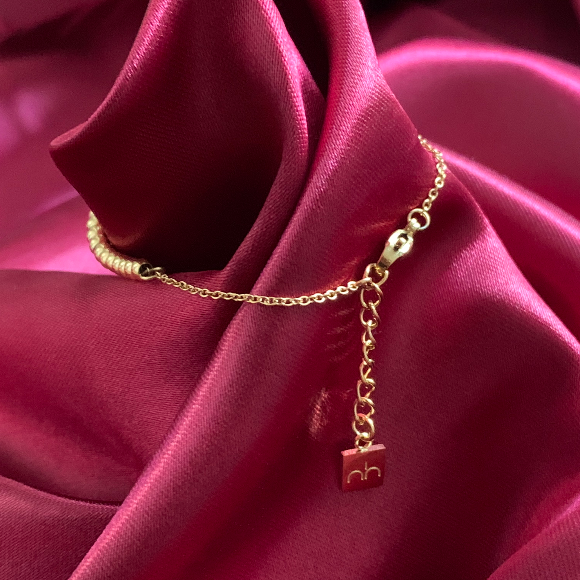 Close up on the gold dainty beaded arabic bracelet chain with Niamh Londons logo engraved