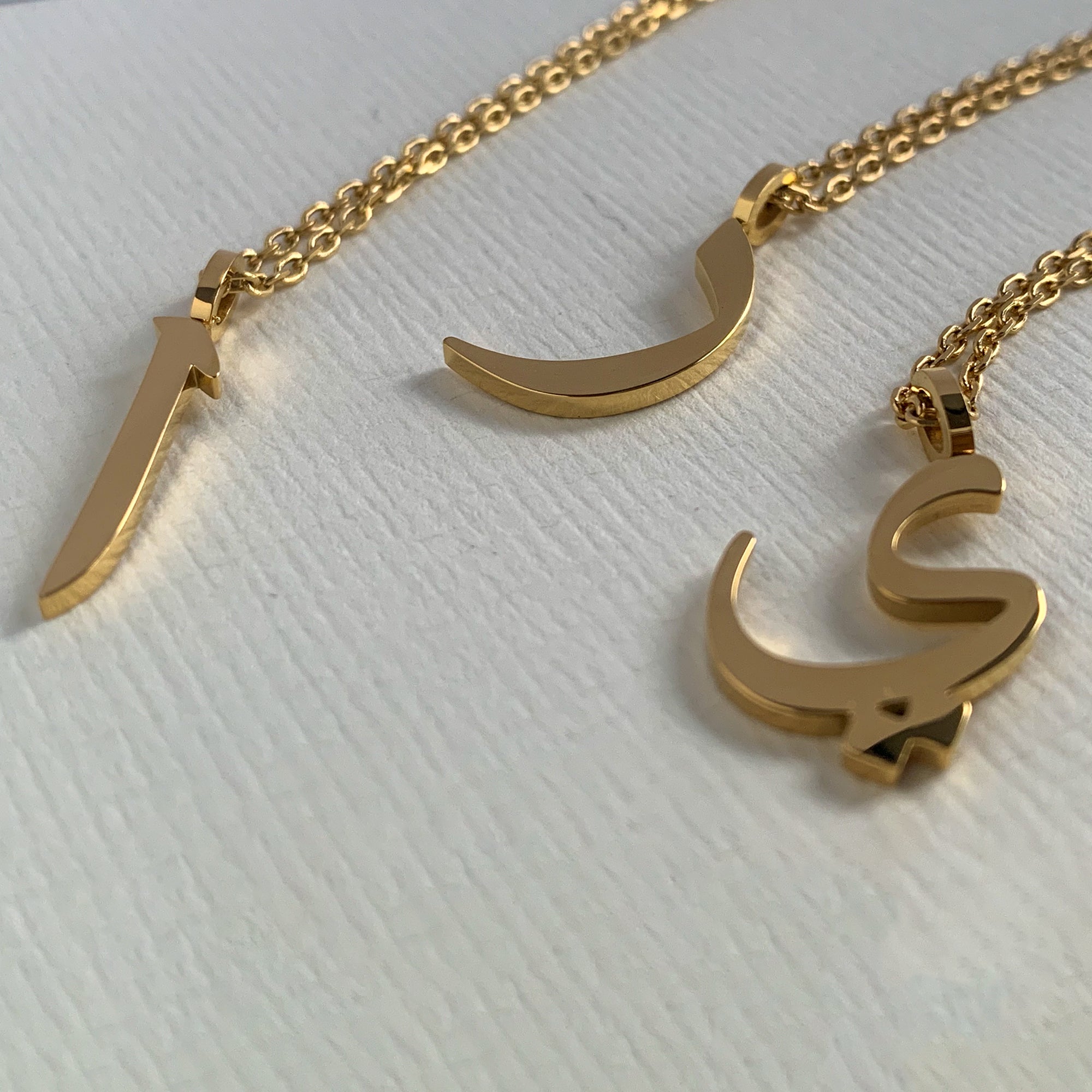 image of three different Arabic letter necklaces in 18K plated gold