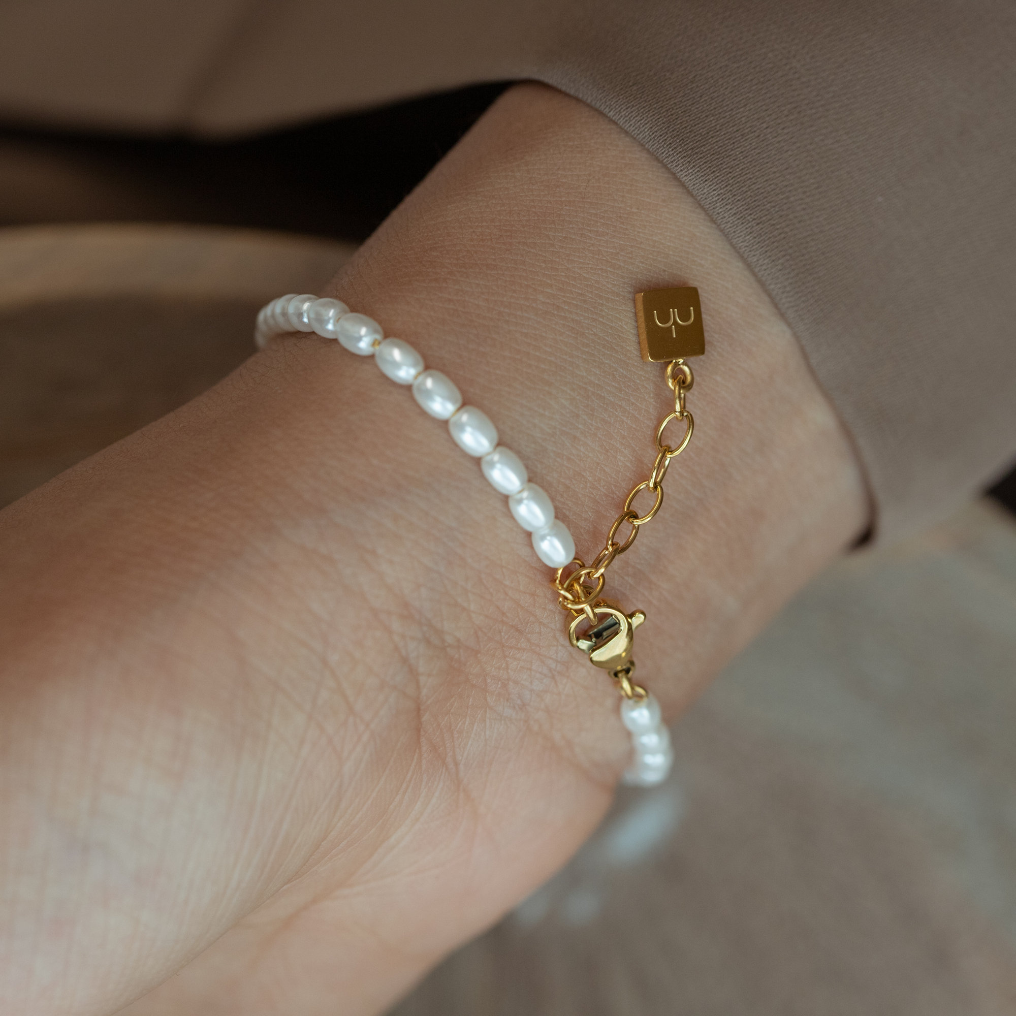 Close up picture of pearl Arabic bracelet chain feature with Nimah London logo