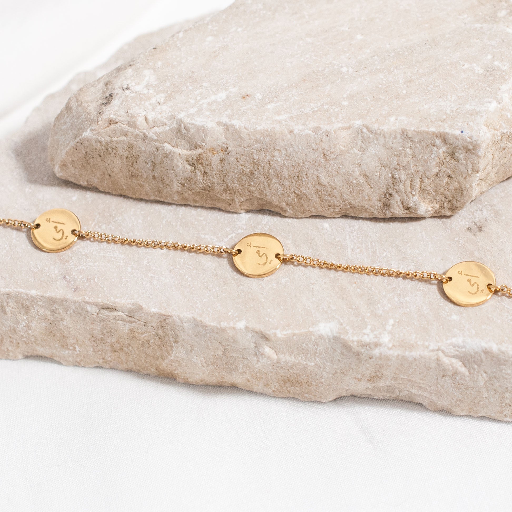 Close up of gold Arabic bracelet engraved with the word 'Mother'