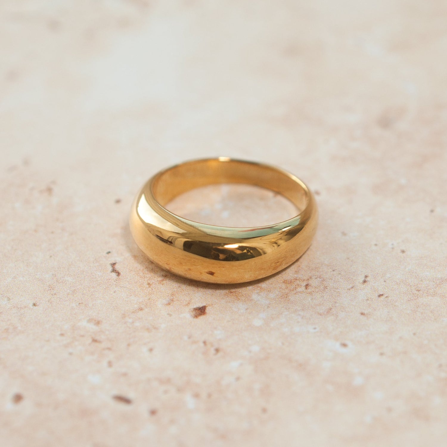 Gold ring on a textured beige surface