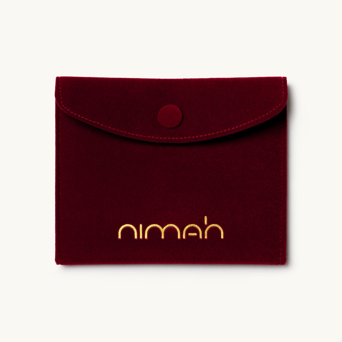 A burgundy felt pouch with a snap button closure and the brand name 'nimah' printed in gold at the bottom, shown on a light off-white background.
