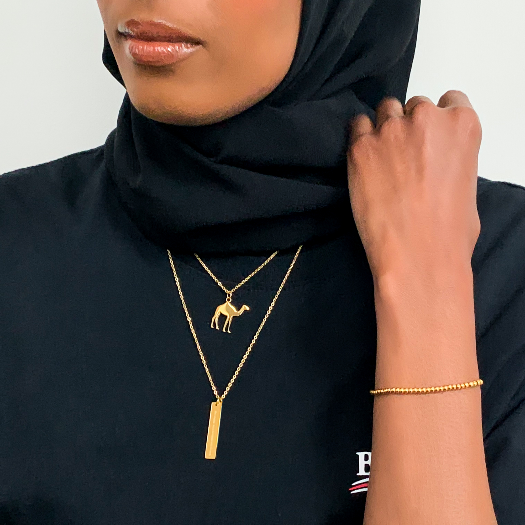 model wearing layered gold Arabic necklaces including camel necklace