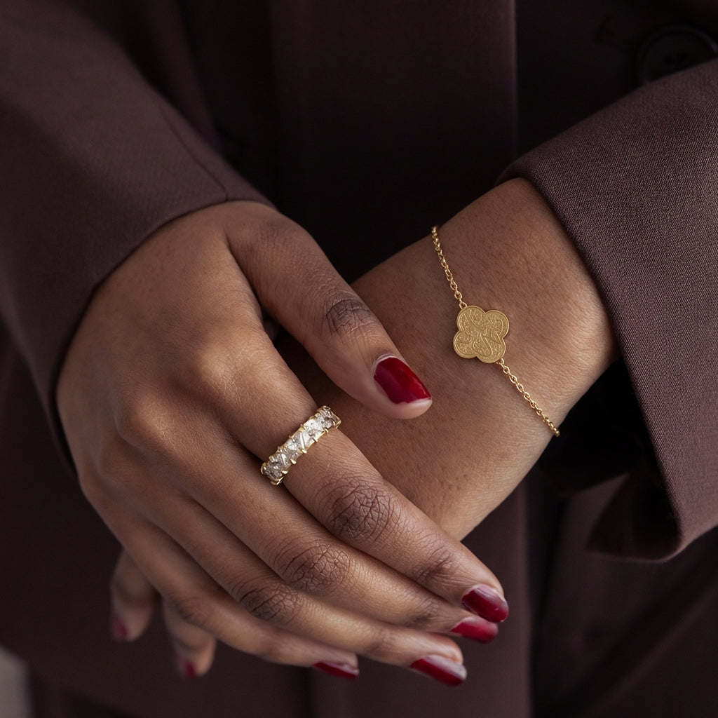 Close-up of a hand wearing a gold ring and bracelet with a dark background