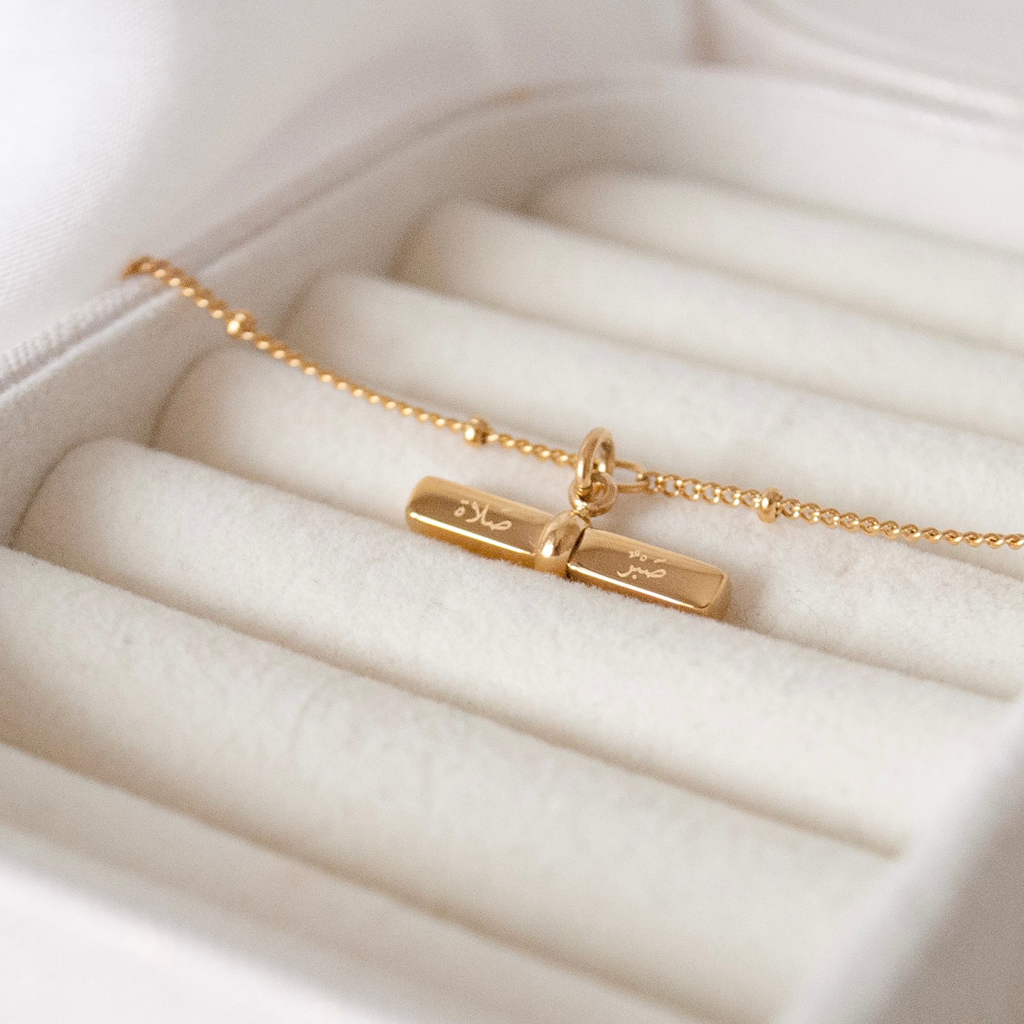 Close up of the 'patience and prayer' engraved arabic gold bracelet charm